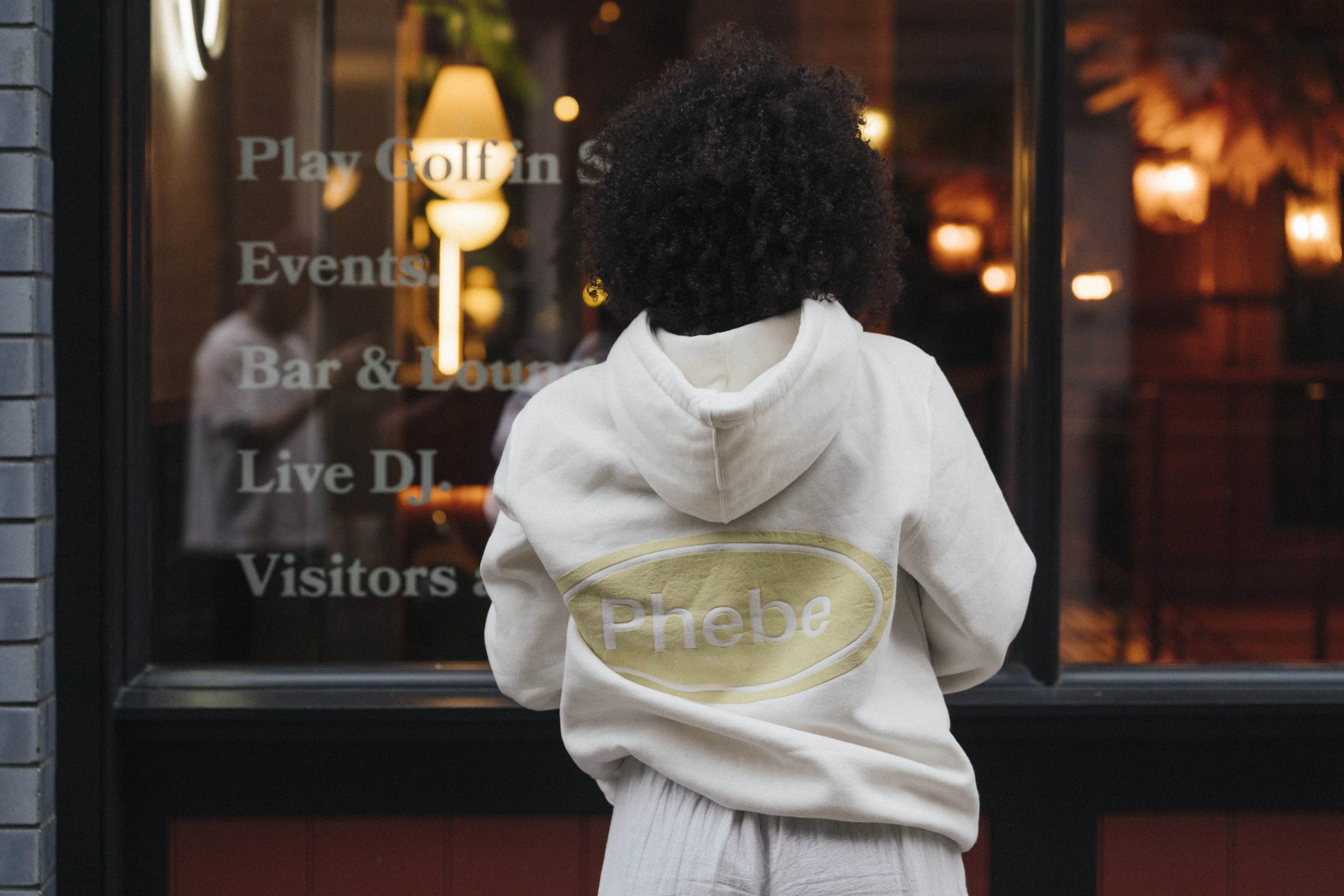 Isabela Santos wearing Phebe Industry in front of a warmly lit window